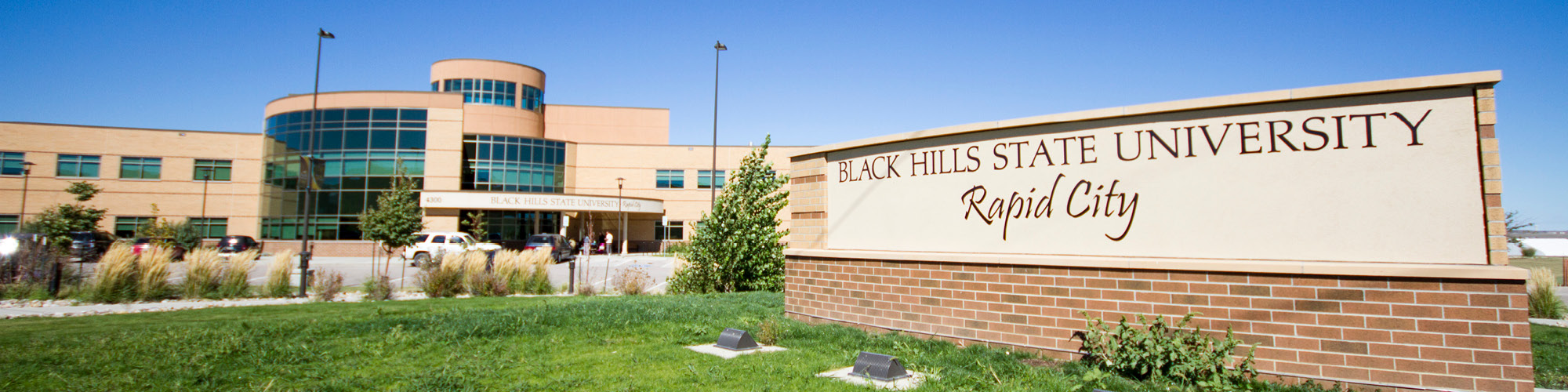 The black hills state university rapid city college campus sign with the building in the background