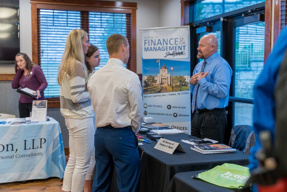 Three BHSU Accounting students asking questions at a booth at a BHSU Accounting Fair.