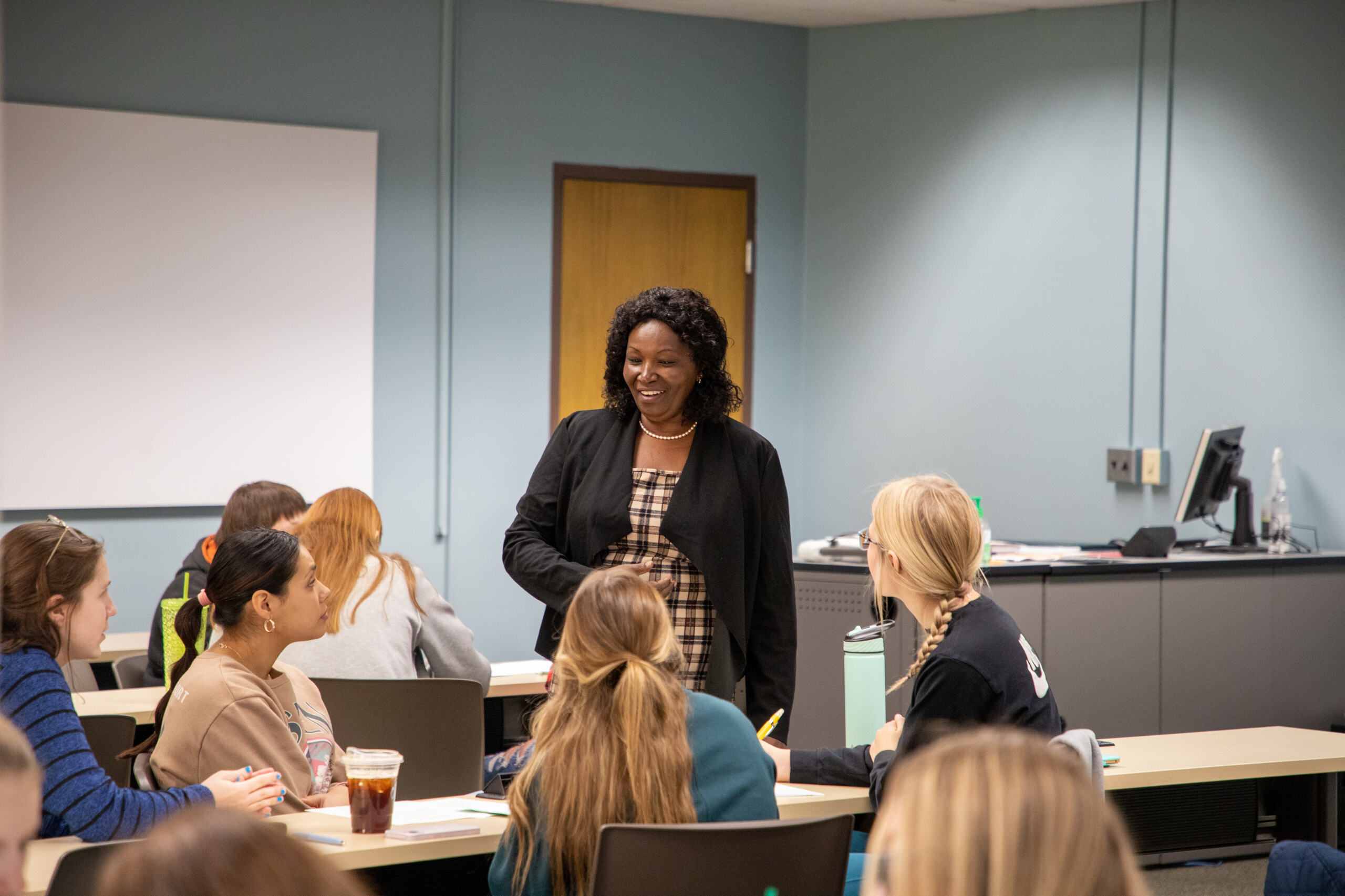 A professor speaks to a group of graduate students in class.