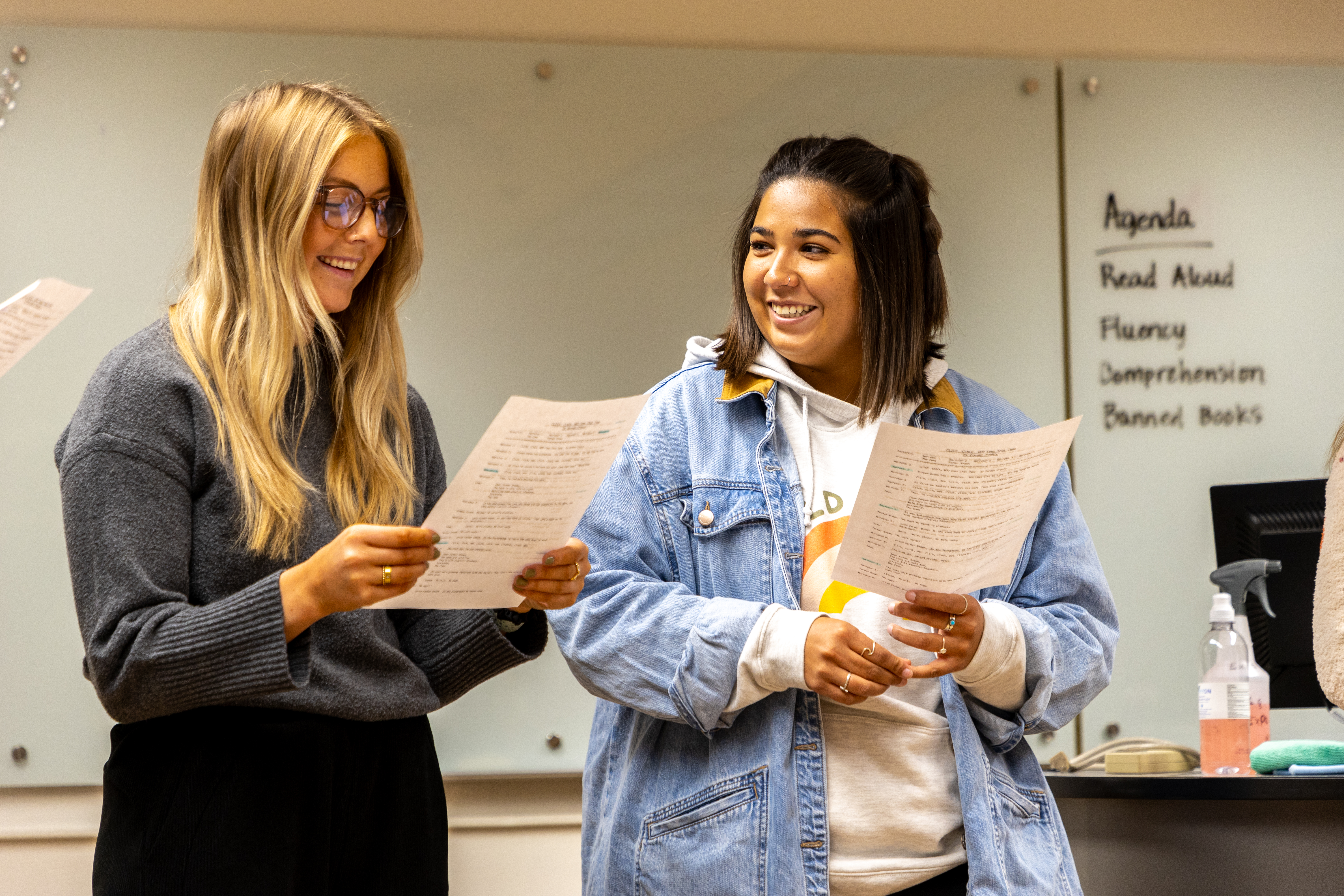 Two Education students standing together, each reading off of a paper that they are holding.