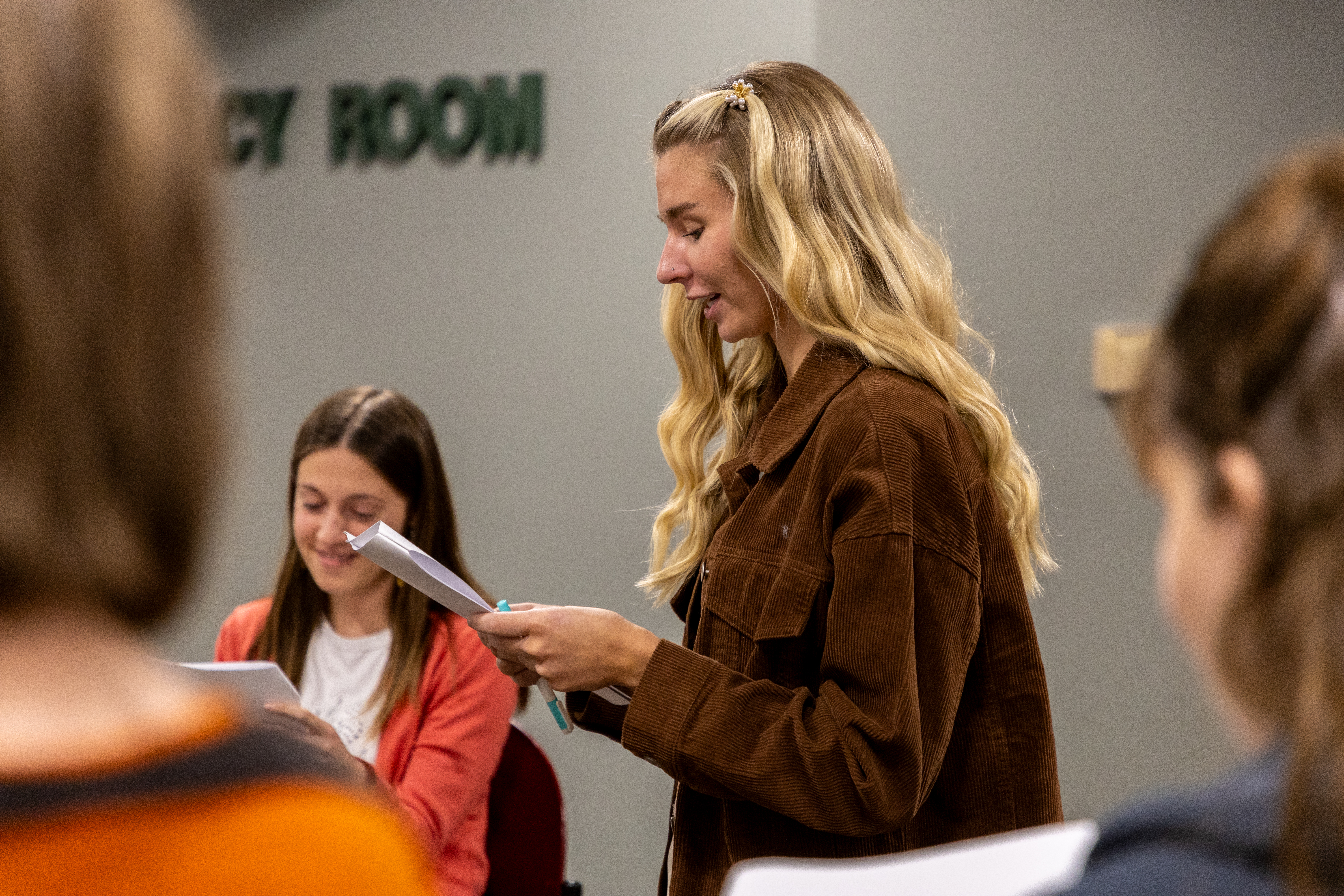 A female BHSU Education student stands profile to the camera reading off of a sheet of paper.
