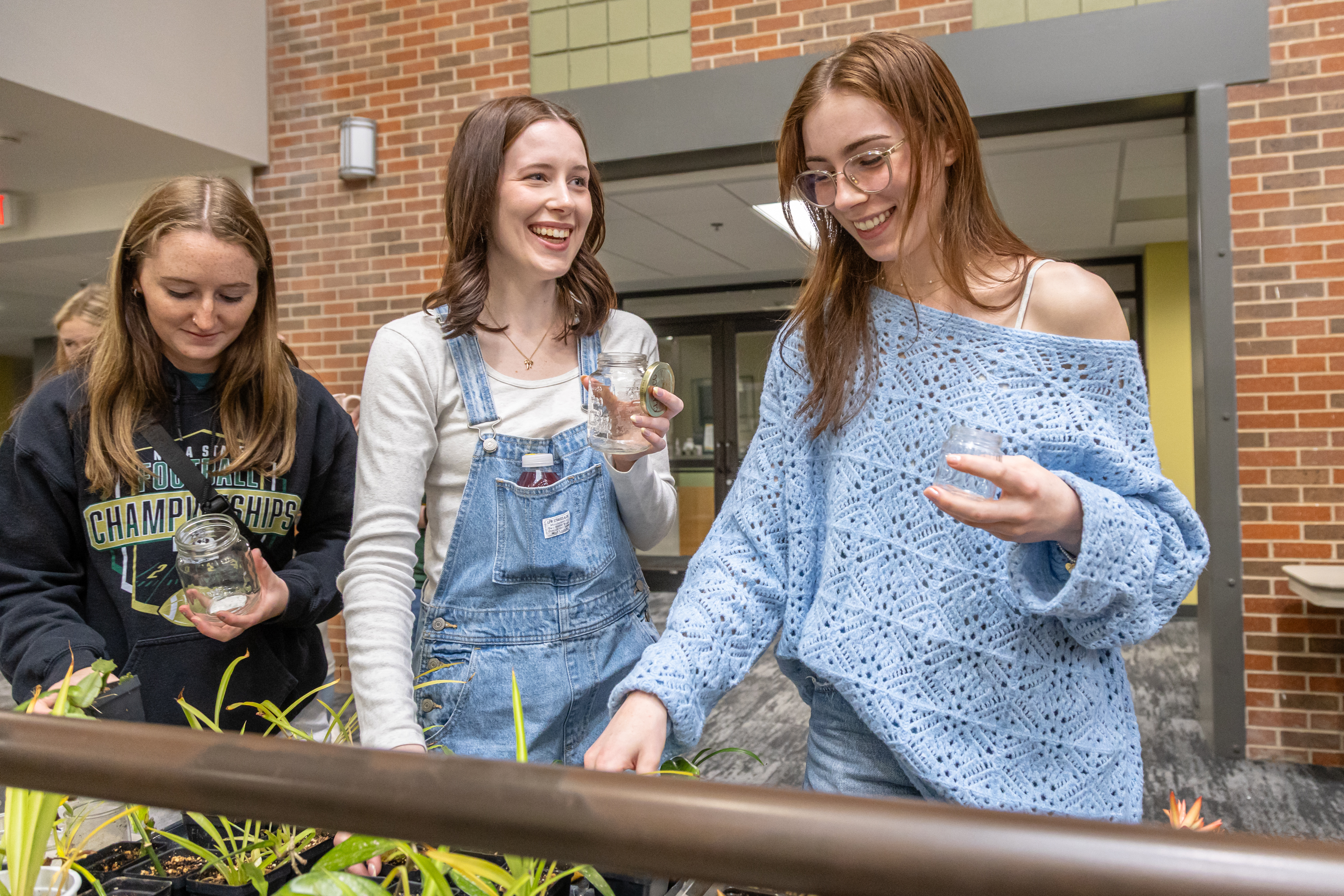 Three female BHSU students take care of plants at the annual Earth Day Festival in the Student Union.