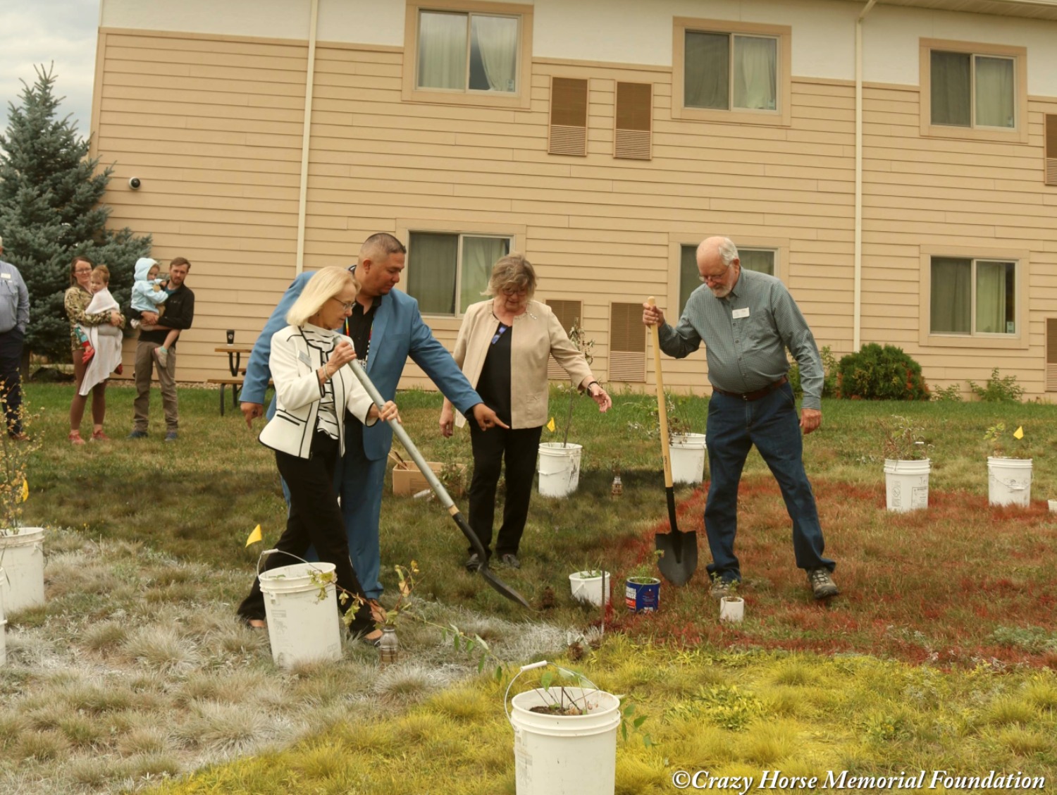 Greenhouse Project In front of a building, two men and two women hold shovels as they work on the greenhouse project