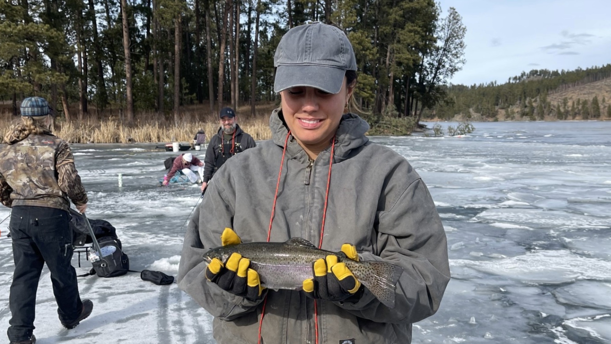 A student holds a fish she just caught from ice fishing