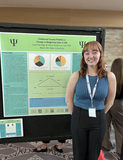 Lexie Bendigo smiling next to her research poster.