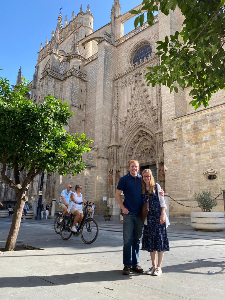 Kelsey Sundberg and Matthias Steeves pose together in front of a building in Spain.